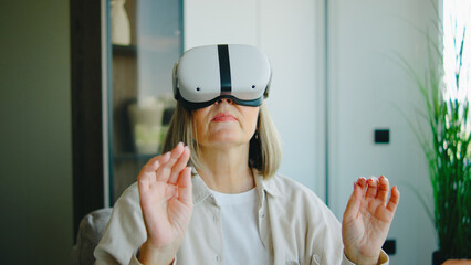 Elderly woman enjoys virtual reality experience while seated in a bright room with plants and modern decor