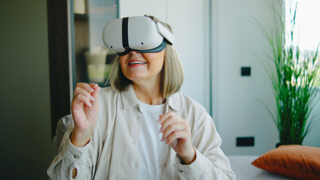 Elderly woman enjoying virtual reality experience indoors at home during daytime