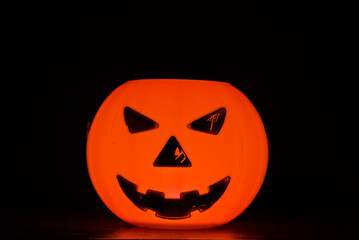 Halloween pumpkin glowing in the dark with spooky face and warm candlelight
