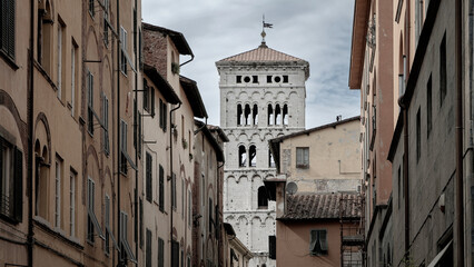 Bell tower of Saint Michael's Cathedral rises above well worn street in Lucca, Italy