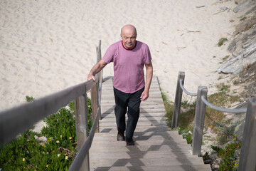 Elderly man walking up the stairs from the beach