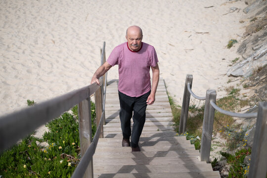 Elderly man walking up the stairs from the beach