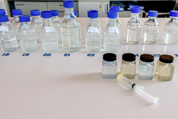 Laboratory storage bottles with blue polypropylene cap and plastic bottles on white table.