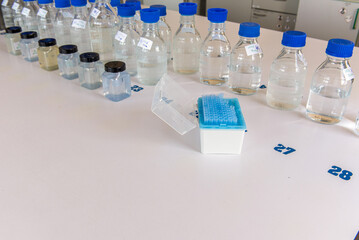 Laboratory storage bottles with blue polypropylene cap and plastic bottles on white table.