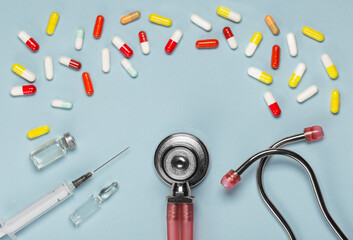 Medical pills and a phonendoscope, top view of a medical syringe and ampoules