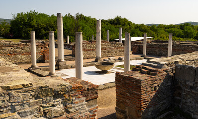 Naklejka premium Under golden summer light, Roman ruins of Felix Romuliana in Gamzigrad, Serbia revealing remains of Corinthian columns, arches and ancient stone walls surrounded by vibrant nature