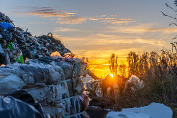 Sunset over a landfill showcasing garbage piles and natural beauty in the distance in late afternoon