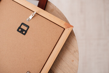 Backside of wooden photo frame with metal hanger, top view on table.