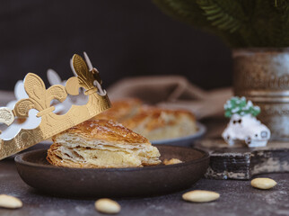 There is a bitten piece of galette on a plate on a dark table.