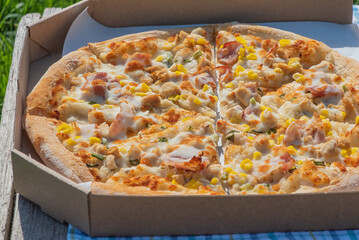 Pizza in a box. Food delivery. Pizza with chicken, bacon, corn.
