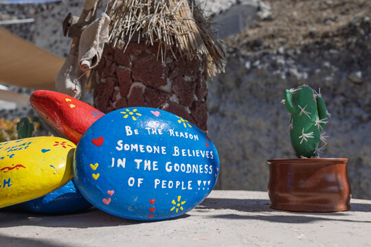 Inspirational painted rock with motivational quote beside small cactus outdoors. Santorini, Greece. 7 October 2025