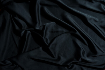 Close up shot showing the texture and folds of a dark black silk fabric
