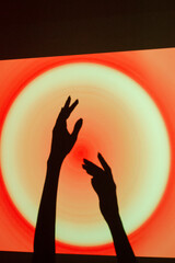 Hands reaching towards a glowing circle on a vibrant red and orange background during a creative event