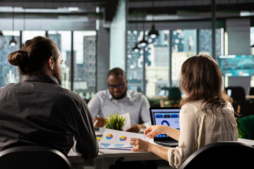 Employees consulting with executive management during a business briefing. Diagrams and visual data...