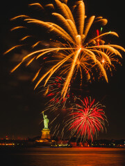 Celebrate the Fourth of July with an enchanting display of fireworks over the Statue of Liberty, illuminating the night sky in vibrant colors against a backdrop of the New York City skyline. © Jin
