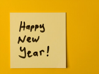 Happy New Year message handwritten on a yellow sticky note