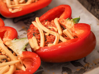Fine red stuffed red peppers with rice, herbs and cheese on wooden cutting board. Premium high quality food with tasty ingredients. Cooking fancy dish. Close up. Selective focus.