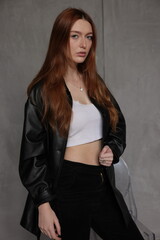 Elegant woman in black leather outfit posing against bold red backdrop, soft cinematic blur, modern fashion editorial style with refined, confident mood.