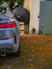 Light blue car parked in a country side home backyard with tall trees in the background. Living in peaceful rural side away from noisy town concept.