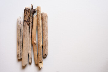 Palos erosionados y desgastados sobre fondo blanco y neutro, situados  al lado izquierdo de la imagen con espacio para texto en el lado derecho. Vista desde arriba.