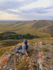 Fototapeta premium Person sitting on rocky terrain overlooking mountainous landscape