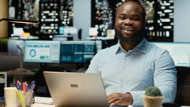 Portrait of male worker immersed in reading emails and researching data for a multinational company, working after hours in a dark office. Focusing on objectives for development.