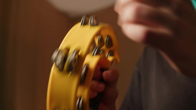 Musical instrument, tambourine Percussion, man playing in studio, sound and creativity. Plastic tambourine in a mans hand.