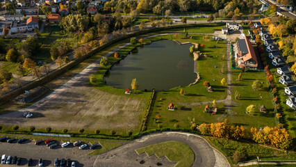 Aerial late afternoon park with oval lake and cottages in Poland