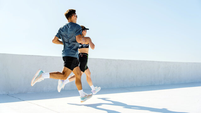 Couple jogging on a rooftop with clear blue sky in a city