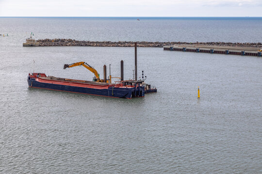A Flatbed Barge and Dredger Operating in the Harbor of Ronne, Bornholm, Denmark 