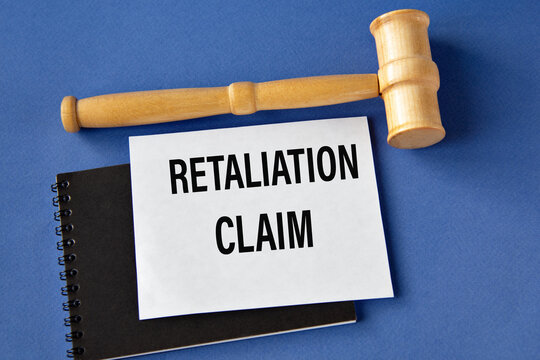 RETALIATION CLAIM - words on a white sheet on a black notebook with a judge's gavel in the background