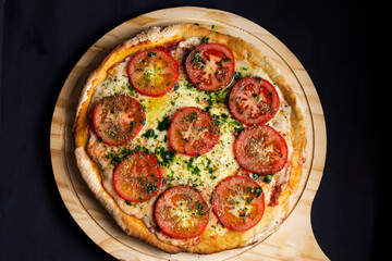 pizza napolitana con tomate y albahaca en tabla de madera