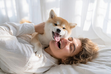 ベッドの上で女性と戯れる柴犬の子犬

