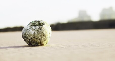 A worn soccer ball lies on the sand of a beach, illuminated by the warm glow of the setting sun, creating a nostalgic atmosphere of play and adventure. - Powered by Adobe