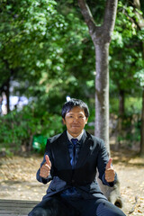 ベンチで親指を立てる笑顔のサラリーマン