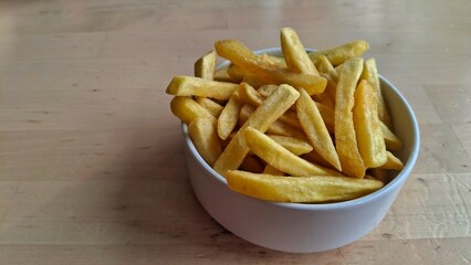 Isolated portion of crispy golden French fries in a white bowl on light background. Minimalist food concept emphasizing texture, color, and simplicity for advertising or menu use.