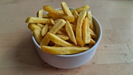 French fries isolated on wooden surface with natural light and clean composition. Perfect for minimalist food design, restaurant branding, or snack product mockup.