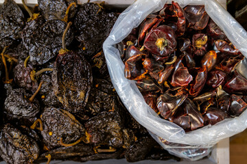 Top view of dried ancho and cascabel chili peppers displayed for sale at market stall