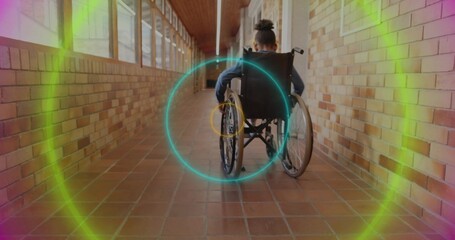 Rolling schoolgirl in wheelchair wearing casual clothes down school corridor with colored overlays