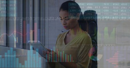 Holding tablet mid adult woman reviewing data in modern office by window, with digital charts