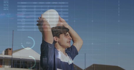 Raising teen wearing navy blue jersey holding white sports ball overhead in backyard, outdoor game