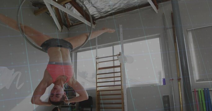Female aerialist performing inverted pose using metal hoop in gym, wearing pink bra and shorts - Powered by Adobe