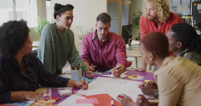 Collaborating creative professionals brainstorming around table in modern office, with color wheel