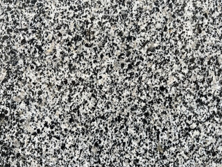 Close-up of polished granite surface with speckled black, white, and gray pattern, showing natural stone texture for backgrounds or material design concepts.