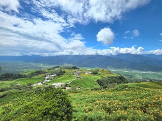 Obraz premium A stunning landscape of lush green mountains, blue sky, and clouds stretching over a wide valley in the East Rift Valley of Hualien and Taitung, Taiwan. 