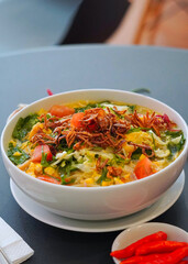 ndonesian Vegetable Soup Soto Betawi with Fried Shallots and Fresh Herbs in White Bowl