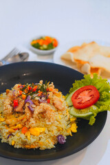 Indonesian Fried Rice with Crackers – Traditional Asian Cuisine. A plate of Indonesian fried rice (nasi goreng), served with crackers, pickles, and fresh vegetables on the side. Traditional Asian cuis