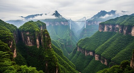 Scenic mountain canyon landscape with dramatic cliffs, lush green forest, mist, and modern suspension bridge
