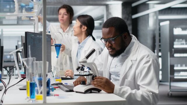 Researcher operating microscope, doing sample observations in laboratory, writing notes. Scientist studies tissue under optical device in biotechnology lab, reporting findings, camera B