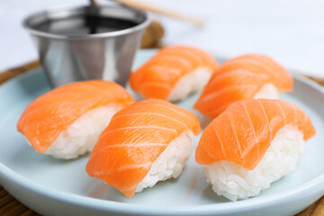 Delicious nigiri sushi with salmon and soy sauce on light grey table, closeup